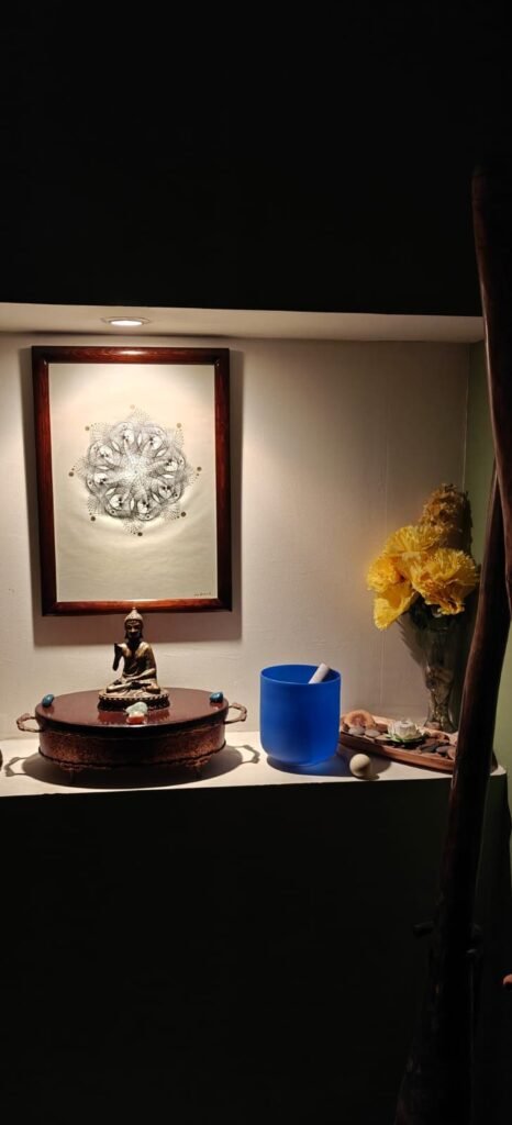 Cuadro de geometría en tinta sobre pared acompañado de flores amarilla y escultura budista.