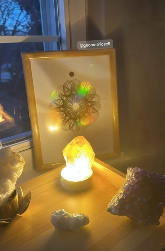 Cuadro de geometría holográfica acompañado de una lámpara luminosa sal y cuarzos.