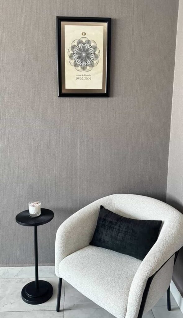 Geometría personal en tinta enmarcada colocada en pared de espacio interior junto a sillón y mesa lateral con decoración minimalista