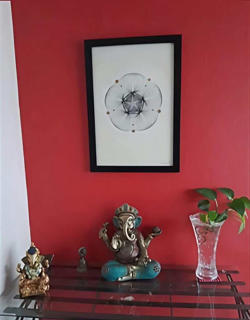 Geometría personal en tinta enmarcada colocada en pared color rojo junto a repisa con piezas decorativas