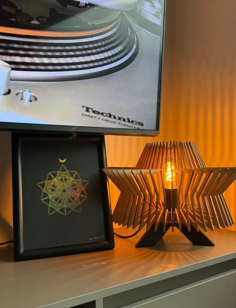 Cuadro de geometría holográfica encima de escritorio a lado de una lámpara con luz naranja